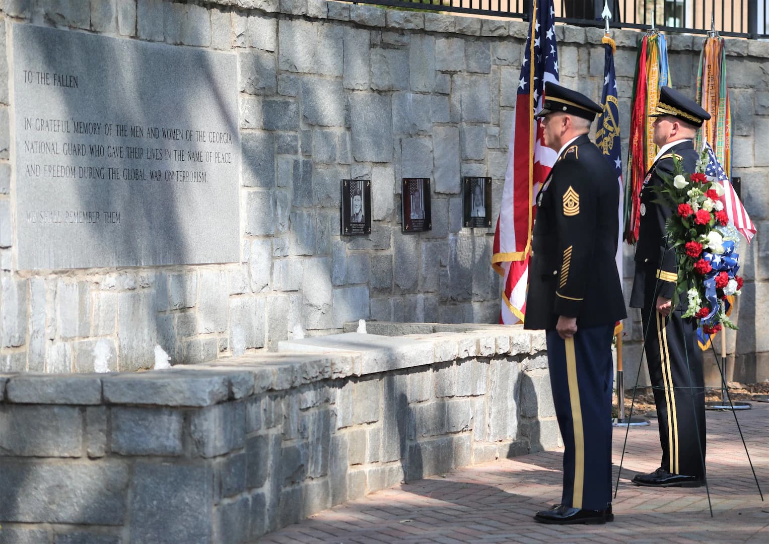 Soldiers in dress uniform standing at attention before the Georgia National Guard Global War on Terrorism memorial wall